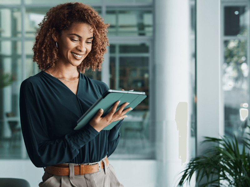 Woman holding a tablet in a modern office environment.